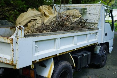 Bahçe bölgesinde ağaç dalları ve enkaz taşıyan bir kamyon.