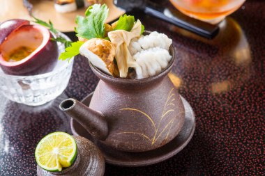 Taze deniz ürünleriyle dolu buharlı seramik çaydanlık.