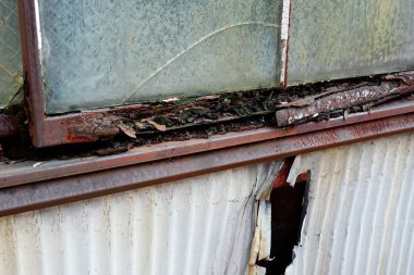 Yıpranmış ahşap çerçeve çürümeyi ve boyayı gösteriyor.