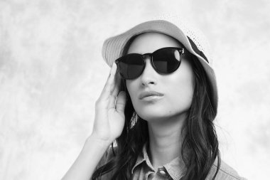 Beyaz arka planda güneş gözlüklü ve şapkalı genç Asyalı kız..