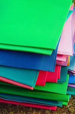 Stacking colorful fabric sheets outdoors on grassy ground
