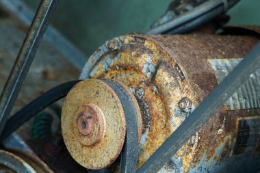Yakın plan paslı, lastik kemerli endüstriyel motoru gösteriyor.