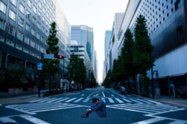 Takım elbiseli üzgün işadamı asfaltta oturup düşünüyor.