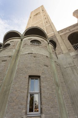 Kemerli pencereleri ve desenli ön cephesi olan yüksek taş bina.