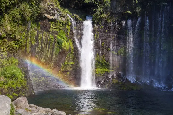 stock image a waterfall with a rainbow in the middle of it 