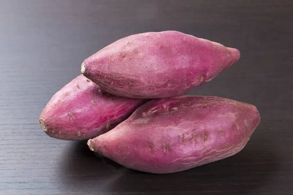 木桌上的生紫红薯 — 图库照片