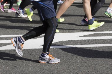 Spor ayakkabılarla koşan bacaklar yol arka planında     