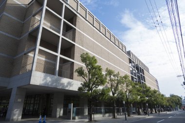 Büyük pencereleri ve dışarıda yeşil ağaçları olan modern beton bina.