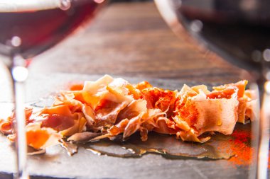 İnce dilimlenmiş jambon ve kırmızı şarap bardakları.