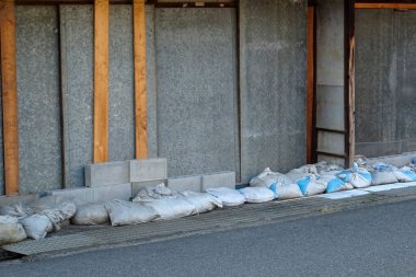 Gri duvara yığılmış malzeme torbaları