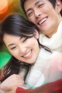 Genç kız arkadaşına sarılan mutlu Asyalı adamın portresi. 