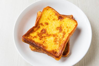 Beyaz tabakta kahvaltıda peynirli tost ve kızarmış yumurta.