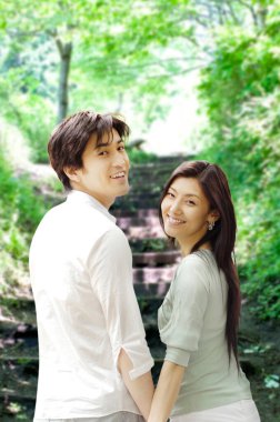 Asyalı mutlu çift parkta yürüyor.