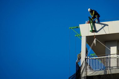 Çatıdaki İnşaat İşçisi Derin Mavi Gökyüzüne Karşı Ekipmanla