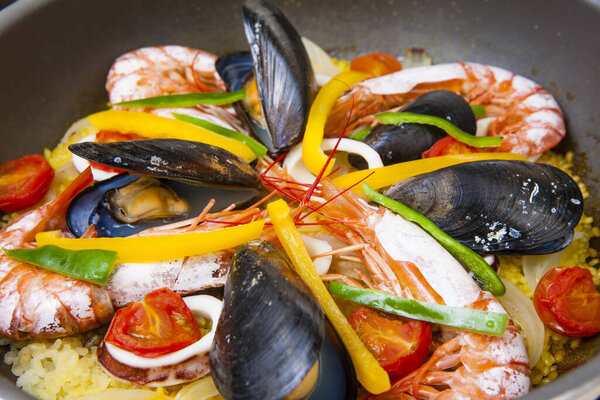 seafood paella in a pan with prawns and mussels. food background. 