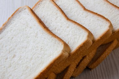 Ahşap masa üzerinde beyaz ekmek dilimlenmiş.