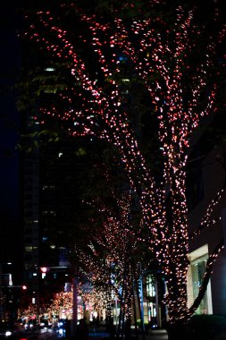 Gece şehrindeki ağaçların üzerinde Noel ışıkları            