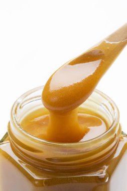 Manuka bal ve kaşık, arka planda lezzetli süper yiyecekler.