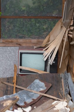 Eski televizyon ahşap döküntüler ve kırık malzemelerle çevrili.