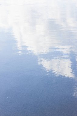 Mavi gökyüzü ve bulutların yansıması ile su yüzeyi arkaplanı 