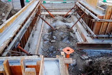 Ahşap iskelet ve beton temeli gösteren inşaat alanı