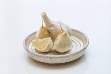 Beyaz bir masada bir kase sarımsak.