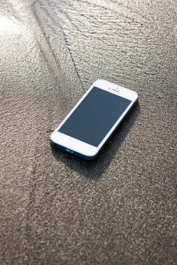 Deniz kıyısındaki kumsalda telefon