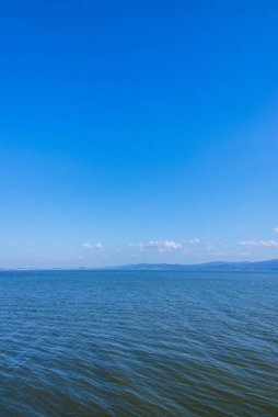 Güzel sahil manzarası, ufuktaki su ve tepeler.         