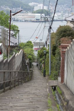 Ahşap merdivenler beton duvarların arasından liman manzarasına doğru iniyor.