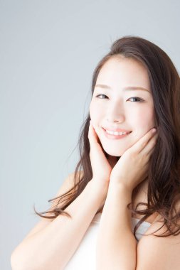 Güzel gülümseyen Asyalı kadın yüzüne dokunuyor