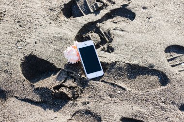 Deniz kıyısındaki kumsalda telefon