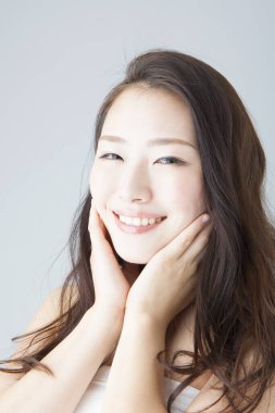 Güzel gülümseyen Asyalı kadın yüzüne dokunuyor