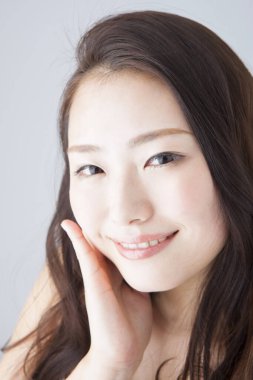 Güzel gülümseyen Asyalı kadın yüzüne dokunuyor