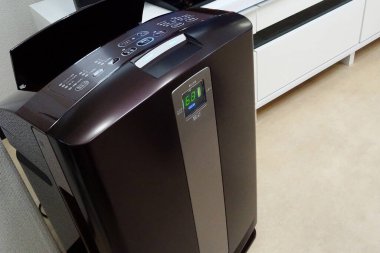 Açık renkli zemine modern hava temizleyici yerleştirilmiş.