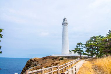 Uzun Beyaz Deniz Feneri Dik, Rocky Kıyı Uçurumunda Duruyor