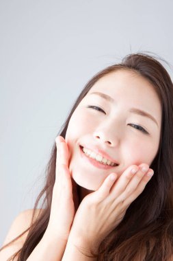 Güzel gülümseyen Asyalı kadın yüzüne dokunuyor