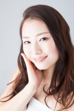 Güzel gülümseyen Asyalı kadın yüzüne dokunuyor