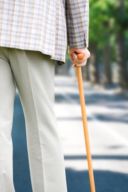 Sokakta bastonlu yaşlı bir adam yürüyor.