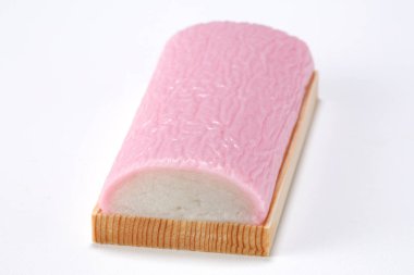Pink and white kamaboko fish cake resting on board