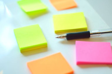 Beyaz masa arkaplanında kalem olan renkli yapışkan notlar