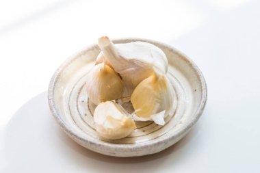 Beyaz bir masada bir kase sarımsak.