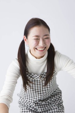 Kareli önlüklü Japon anaokulu öğretmeni stüdyo arka planında sarılıyor.