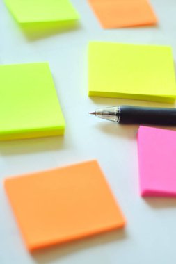 Beyaz masa arkaplanında kalem olan renkli yapışkan notlar