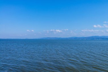 Güzel sahil manzarası, ufuktaki su ve tepeler.         