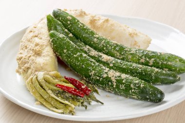 Masada ekmek kırıntıları olan bir tabak turşu.