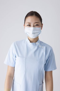 Beyaz arka planda nefes maskesi takmış güzel Japon kadın doktorun portresi.