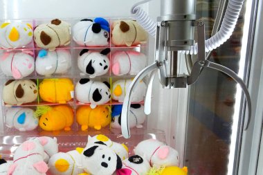 Renkli peluş oyuncaklar ve hayvanlarla dolu bir pençe makinesi.