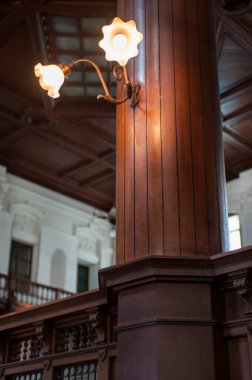 Büyük ahşap sütunları aydınlatan klasik bir lamba.