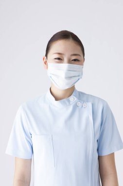 Beyaz arka planda nefes maskesi takmış güzel Japon kadın doktorun portresi.