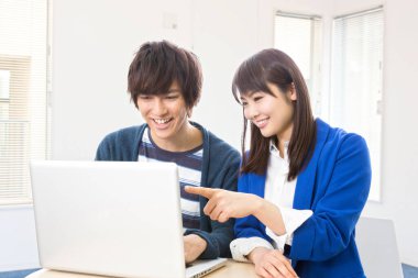 Laptop kullanan iki genç Asyalı öğrenci.